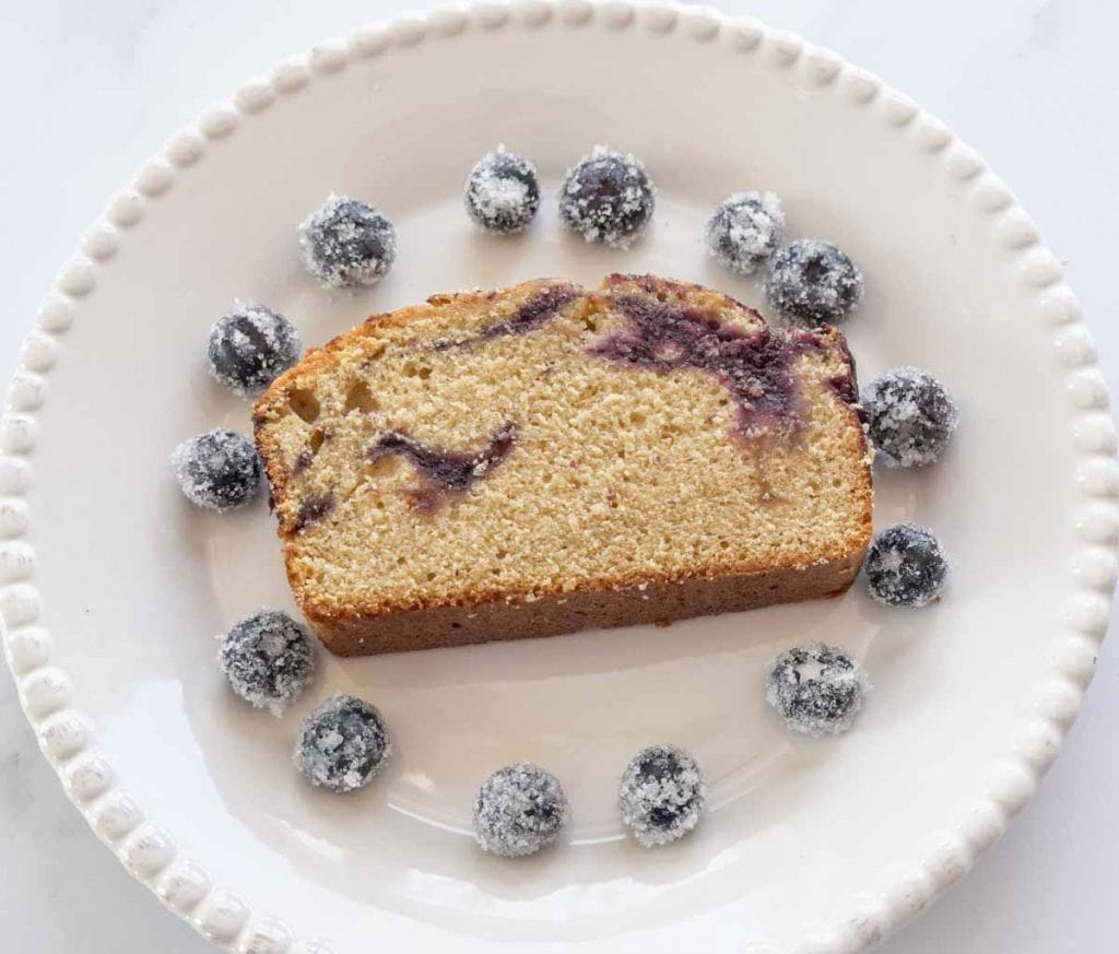 slice of blueberry swirl pound cake with "sugared" blueberries on white plate