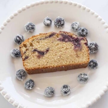 slice of blueberry swirl cake with sugared blueberries on white plate