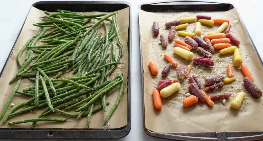 String beans and baby carrots on baking sheet