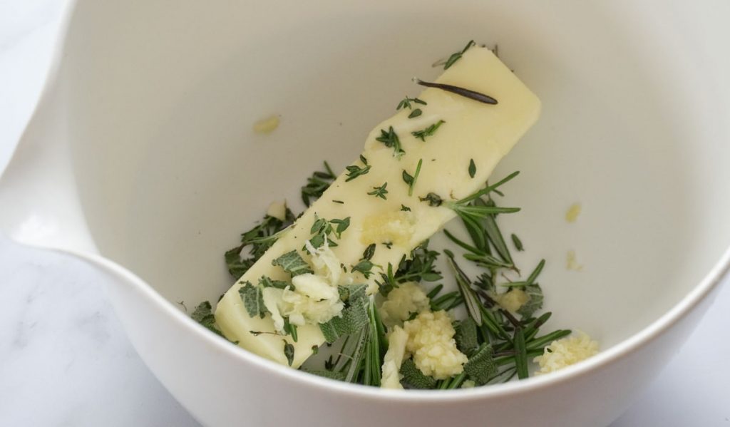 stick of butter and minced fresh herbs in a bowl