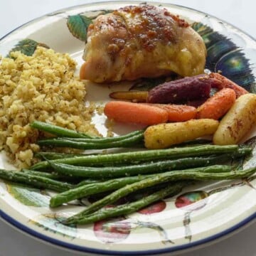 low carb sweet garlic chicken with riced cauliflower, string beans and carrots on dinner plate