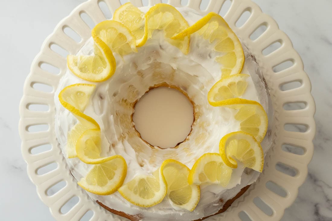 keto lemon yogurt cake with lemon glaze on white cake plate