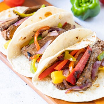 steak fajitas on board, peppers, salsa, tomato.