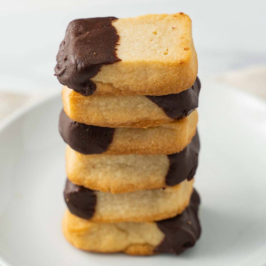 keto shortbread cookies dipped in chocolate in a stack on a white plate