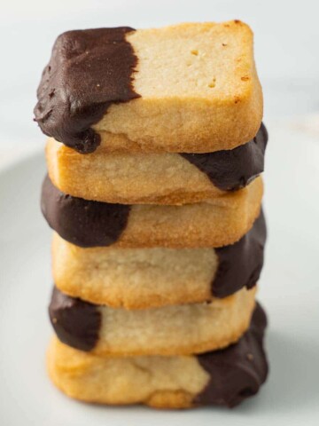 keto shortbread cookies dipped in chocolate in a stack on white plate