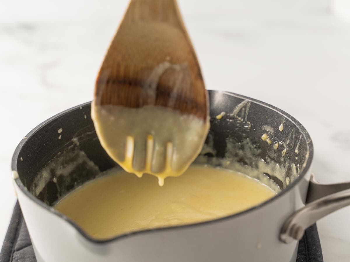 coconut cream pudding in saucepan with wooden spoon