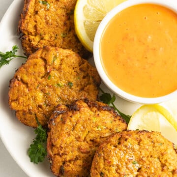 Air fryer crab cakes with lemons, sauce on white plate