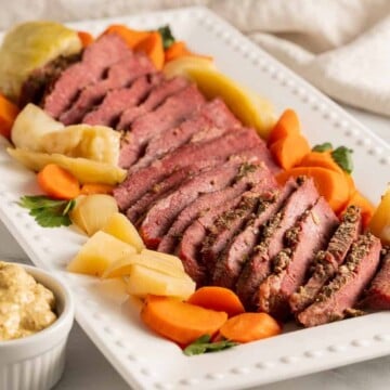 dutch oven corned beef with carrots, cabbage, parsnips on white platter