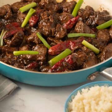 sliced beef, chili peppers in pan with cauliflower rice