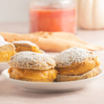 keto pumpkin donuts on white plates, orange candle, white pumpkin.