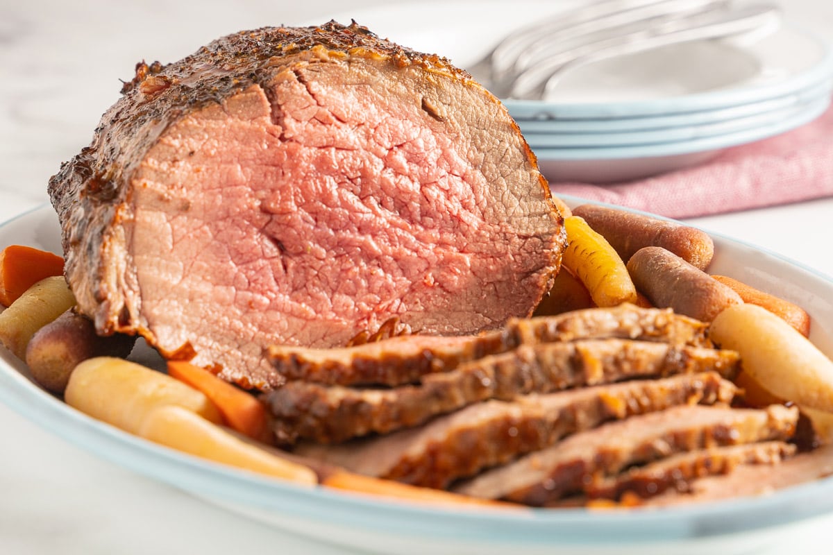 Roast beef with carrots on white platter.