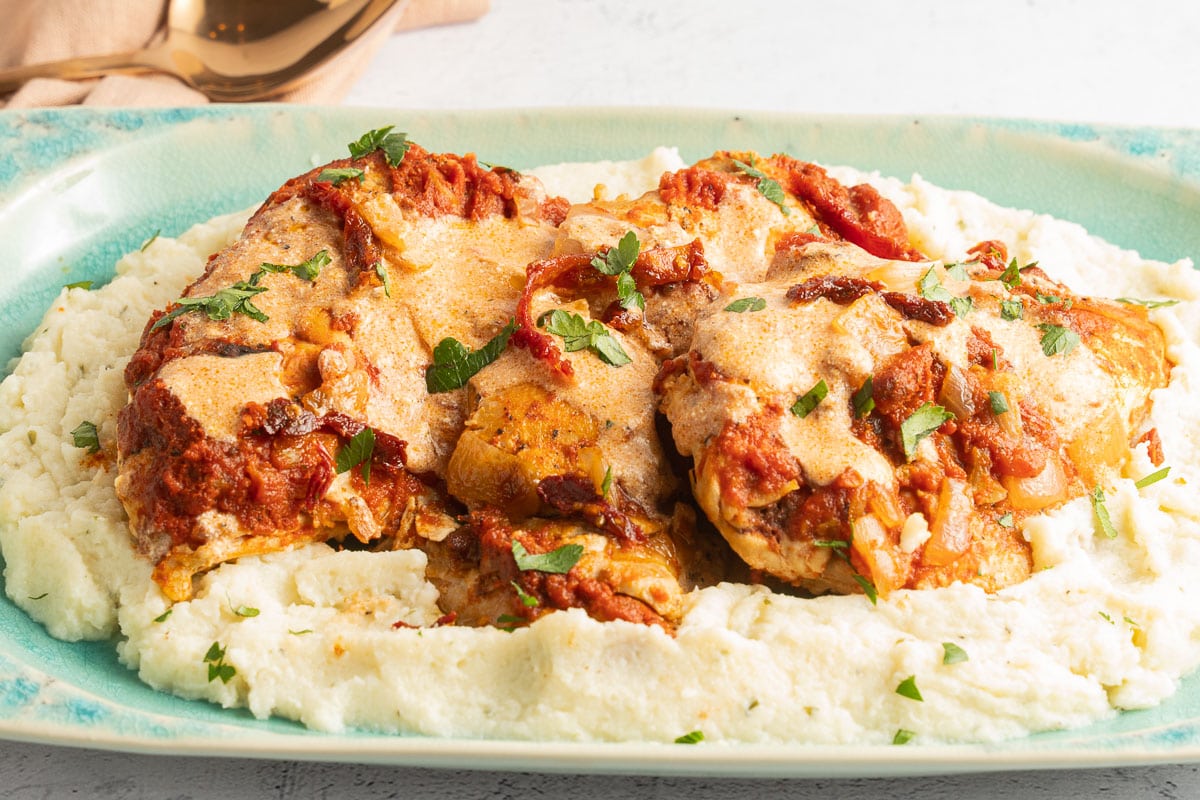chicken paprika and mashed cauliflower on a green platter.