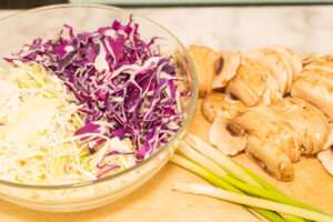 red, white cabbage in bowl, sliced mushrooms, scallions.