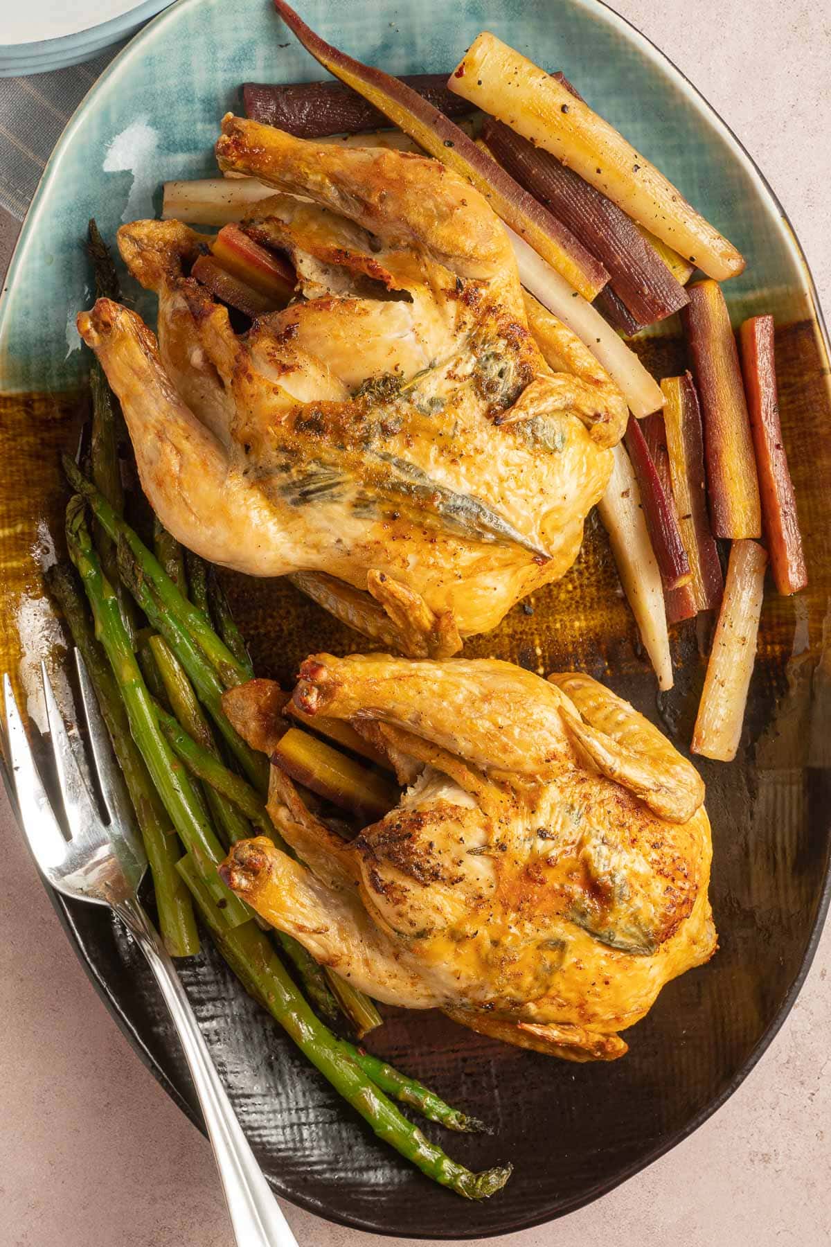 Cornish hens on platter with vegetables.