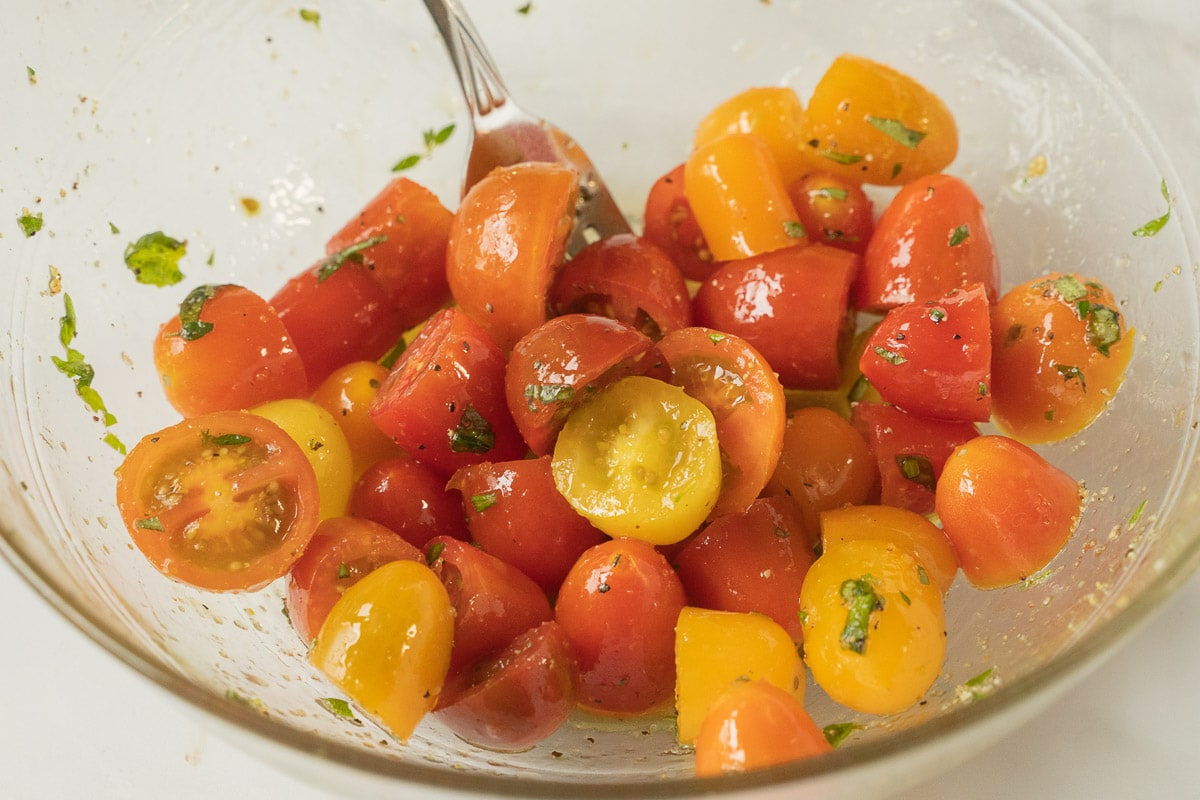 cherry tomatoes, herbs in glass bowl.