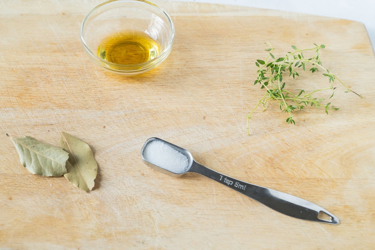 thyme, olive oil, bay leaves, salt on cutting board.