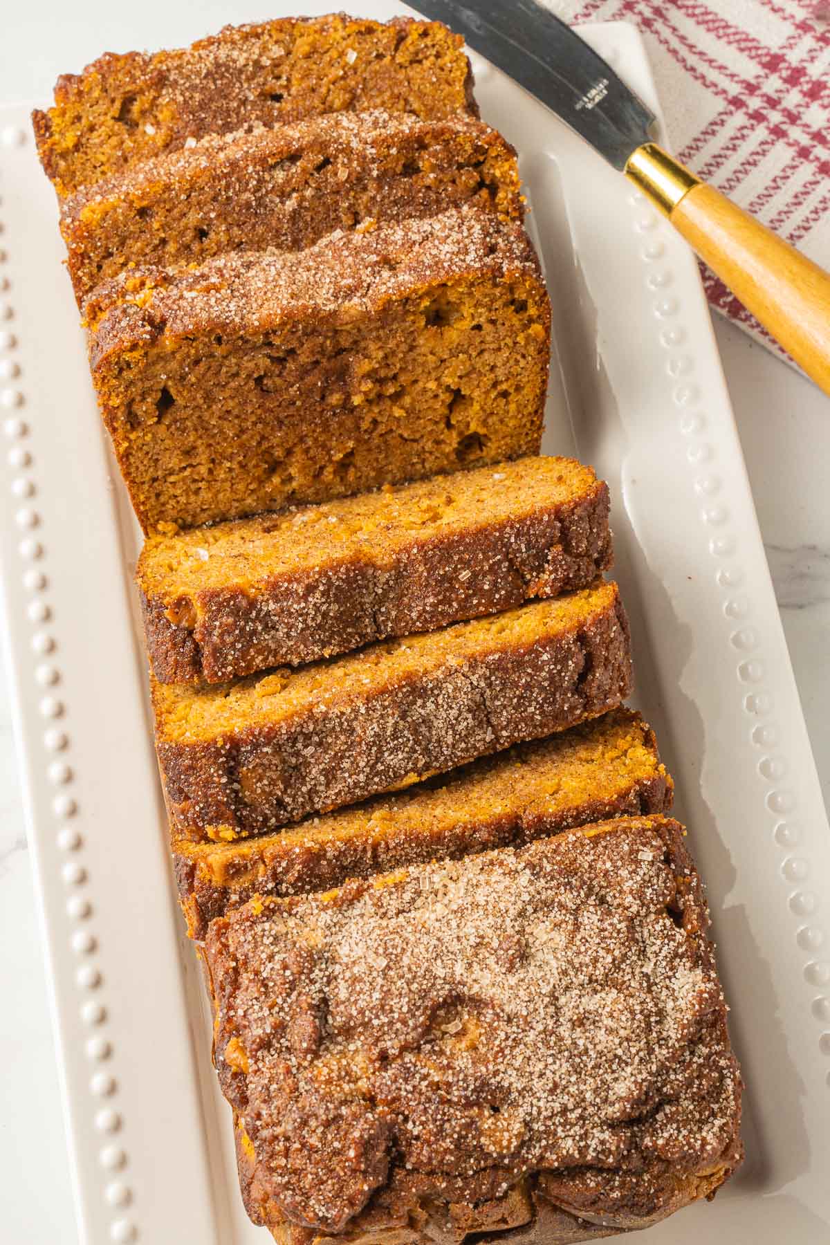 keto pumpkin butterscotch bread on white platter with knife and napkin.