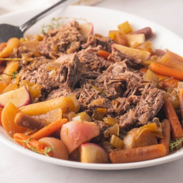 Platter of pot roast, carrots, radishes and turnips.