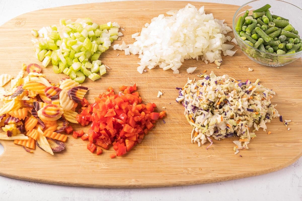 chopped celery, cabbage, carrots, onion, red pepper on cutting board.