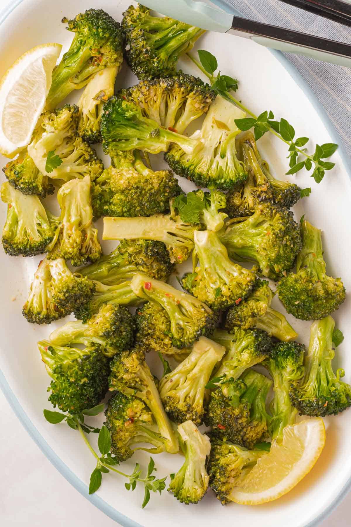 Marinated broccoli and lemon on white platter.