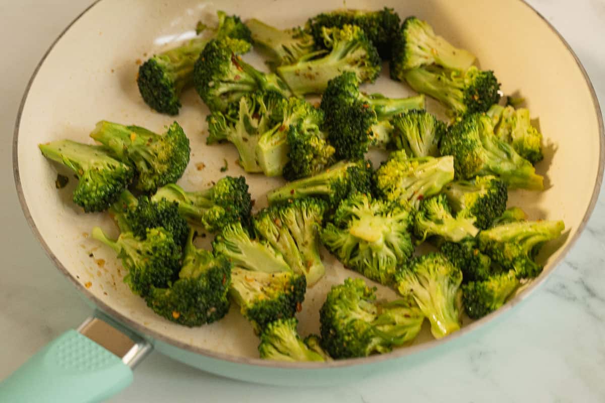 Sautéed marinated broccoli in fry pan.