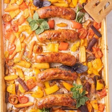 Sausage, peppers, onions, carrots on baking sheet.