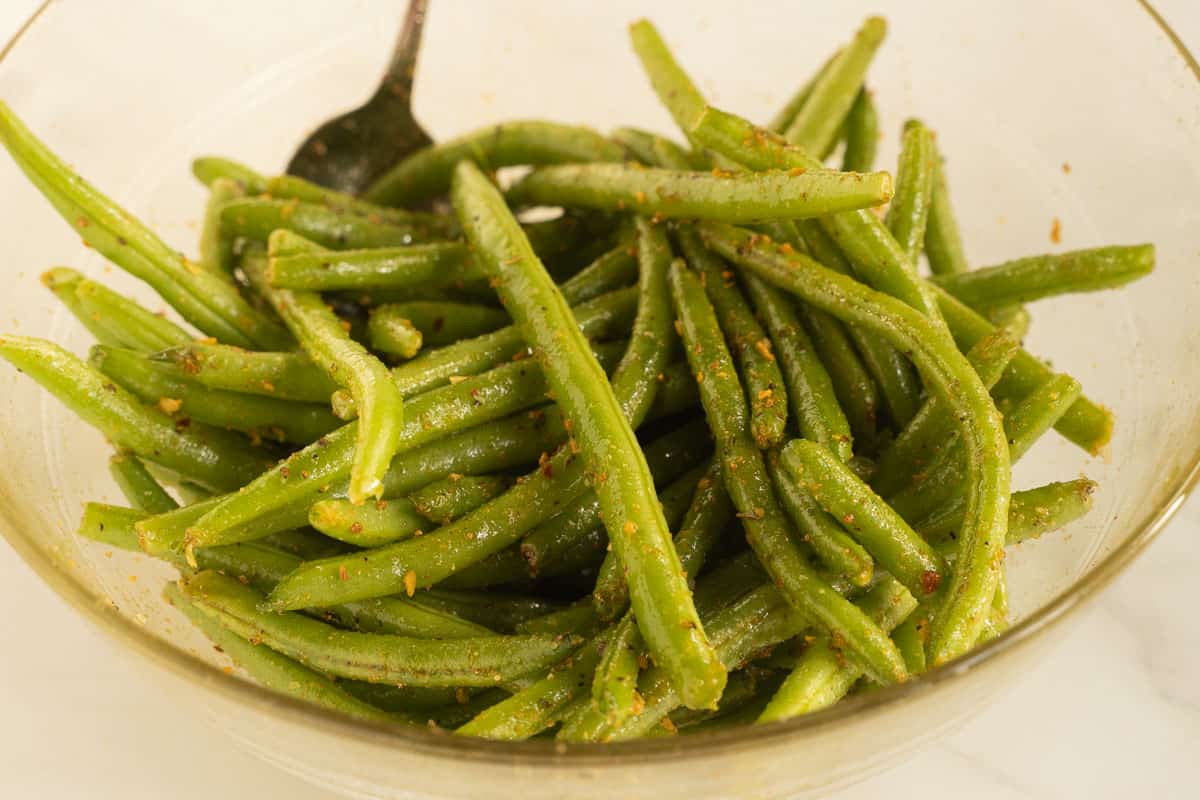 Seasoned green beans in glass bowl.