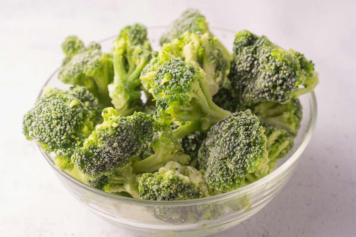 Frozen broccoli florets in glass bowl.