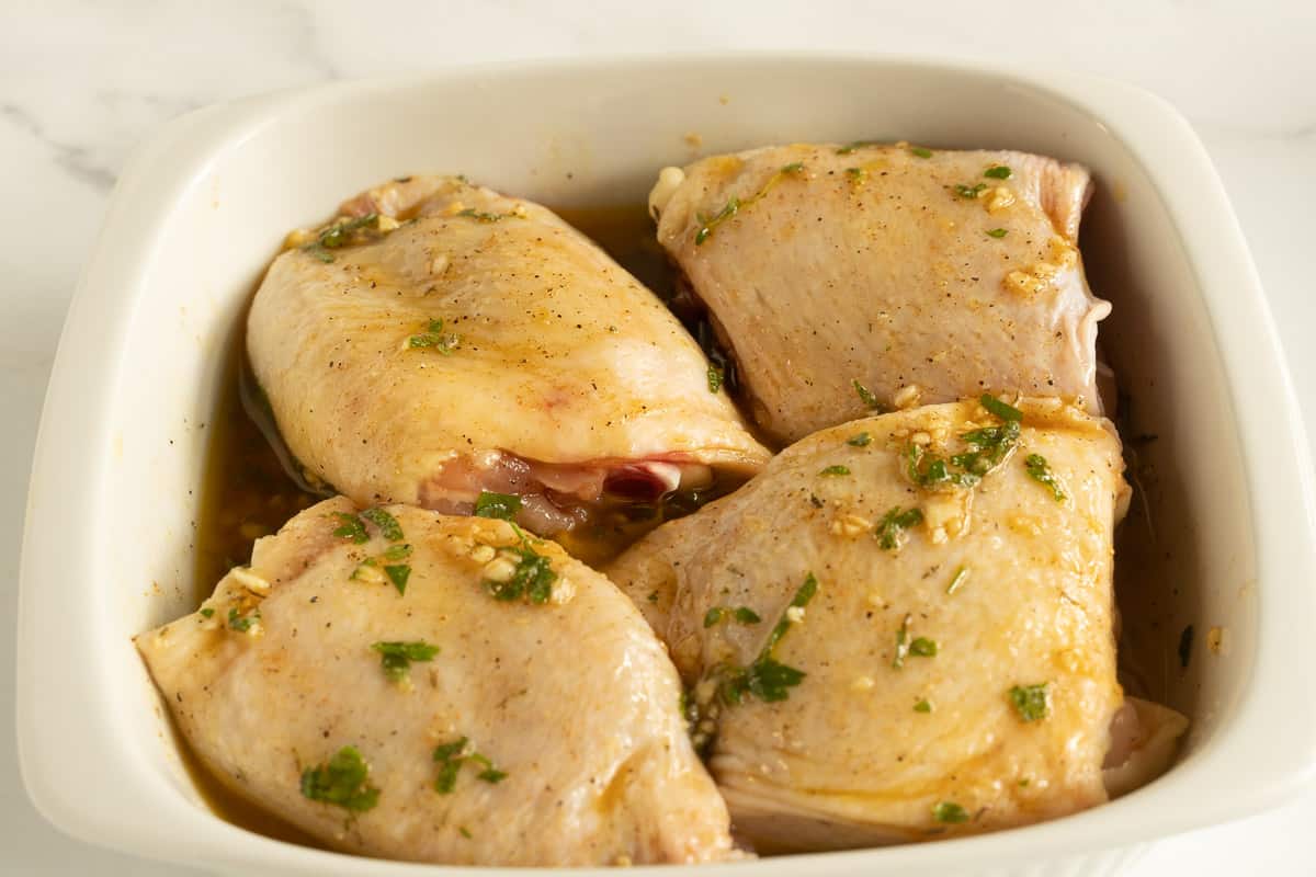 Marinated chicken thighs in white bowl.