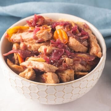 Pork and cabbage stir fry in white bowl.