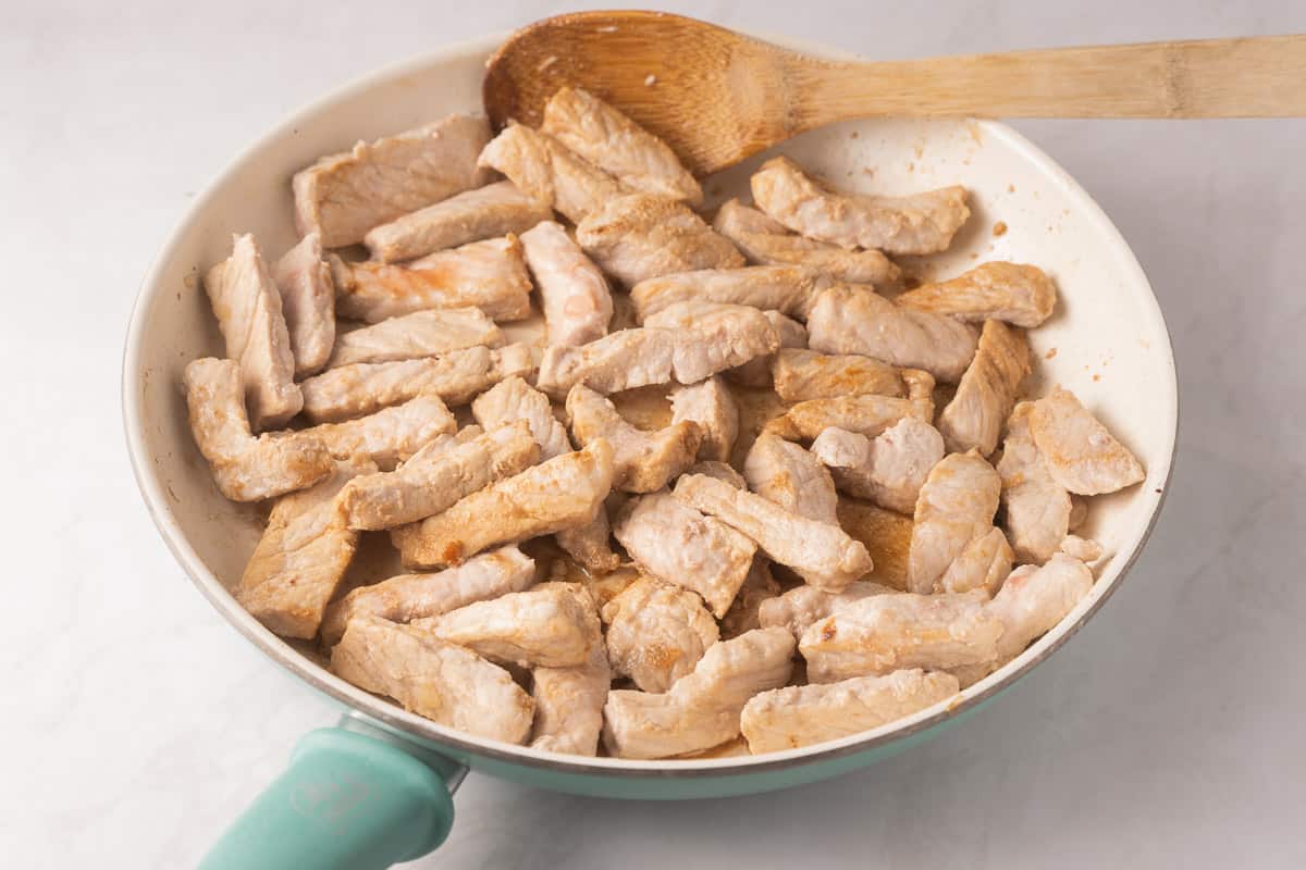 Fried sllcied pork in skillet.