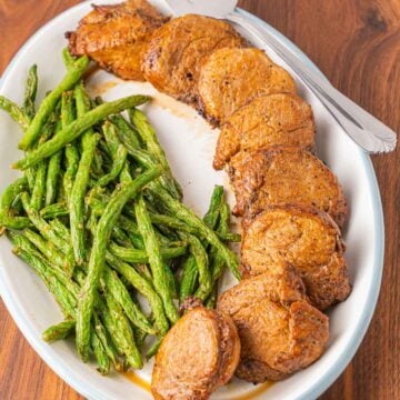 Air fryer pork tenderloin medallions and green beans on platter,