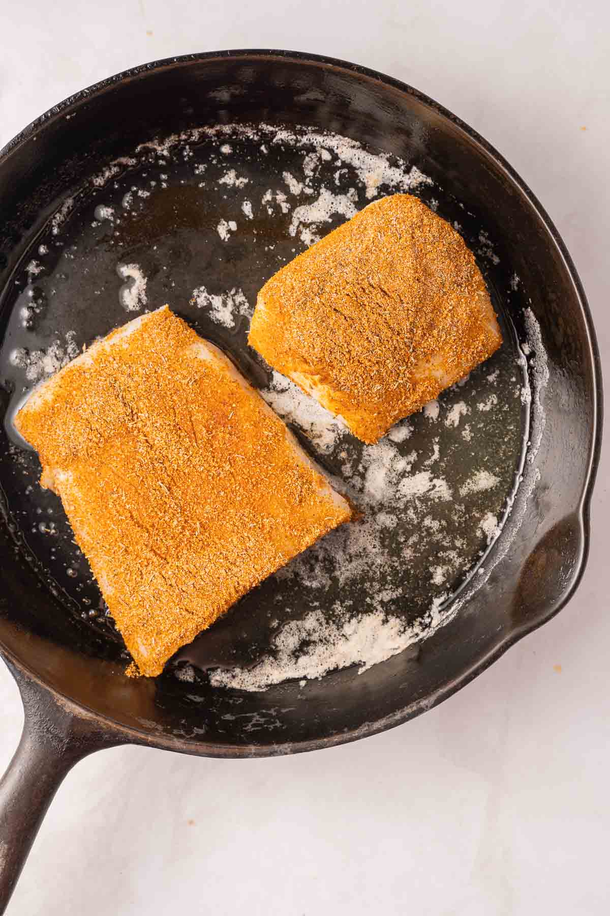 Blackened sea bass in hot skillet.