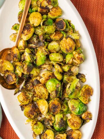 Charred Brussels sprouts on white platter.