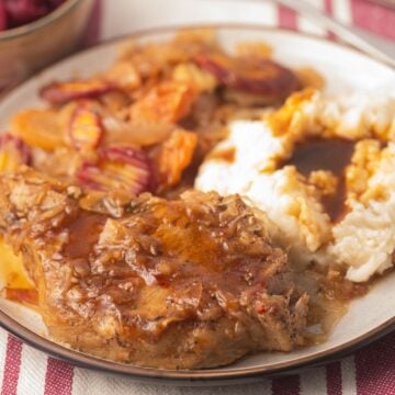 Pork chops, carrots, sauerkraut, mashed potatoes and gravy on plate.