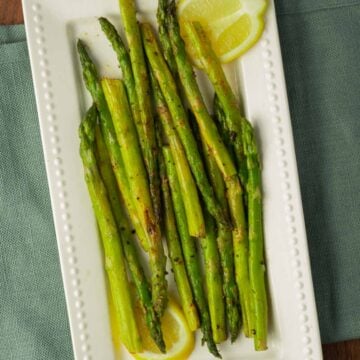 Pan Seared Asparagus and lemon on white plate.
