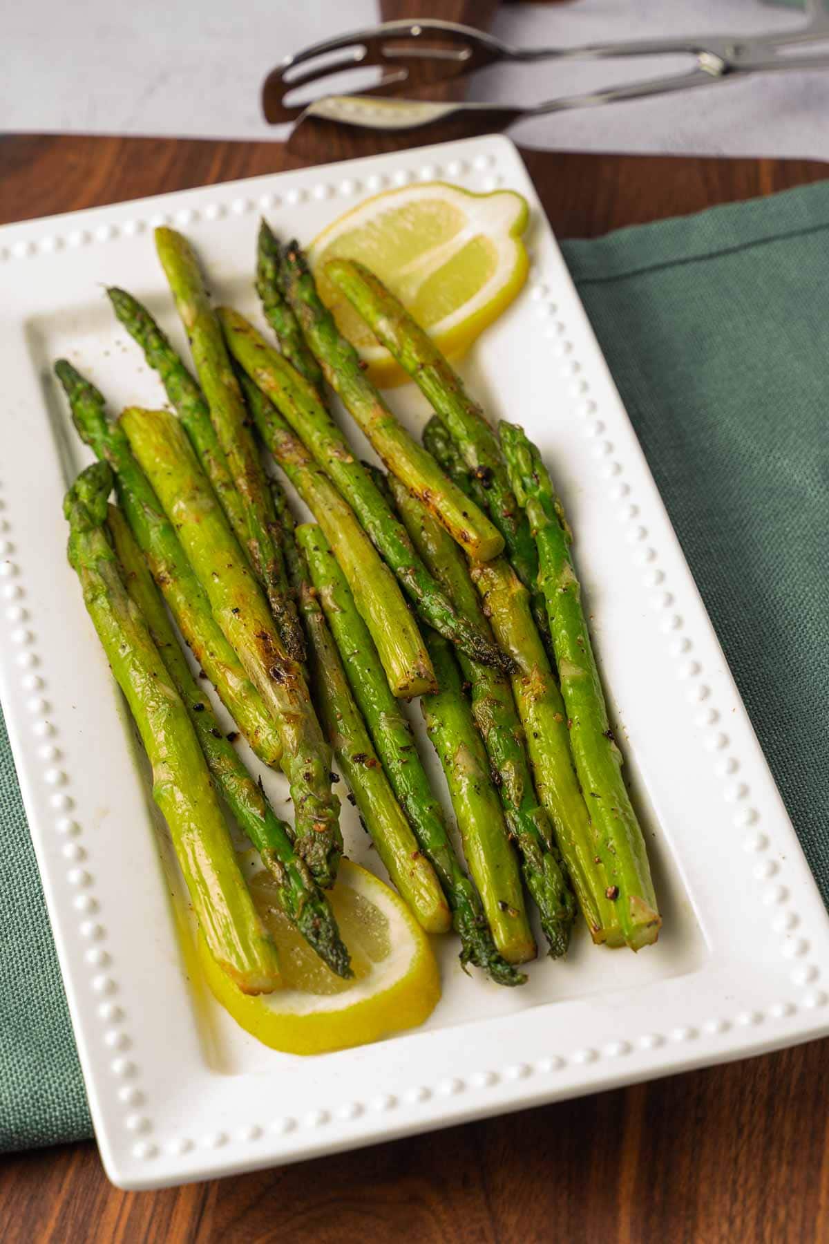 Pan Seared Asparagus and lemon on white plate.