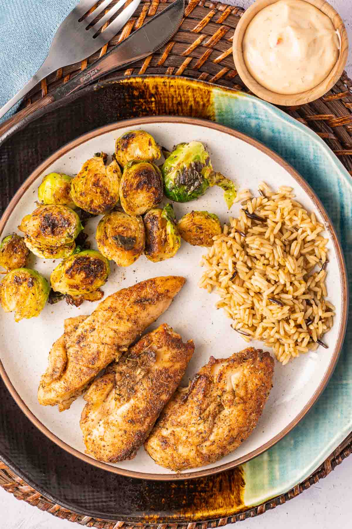 Chicken tenders, rice, brussels sprouts on plate.