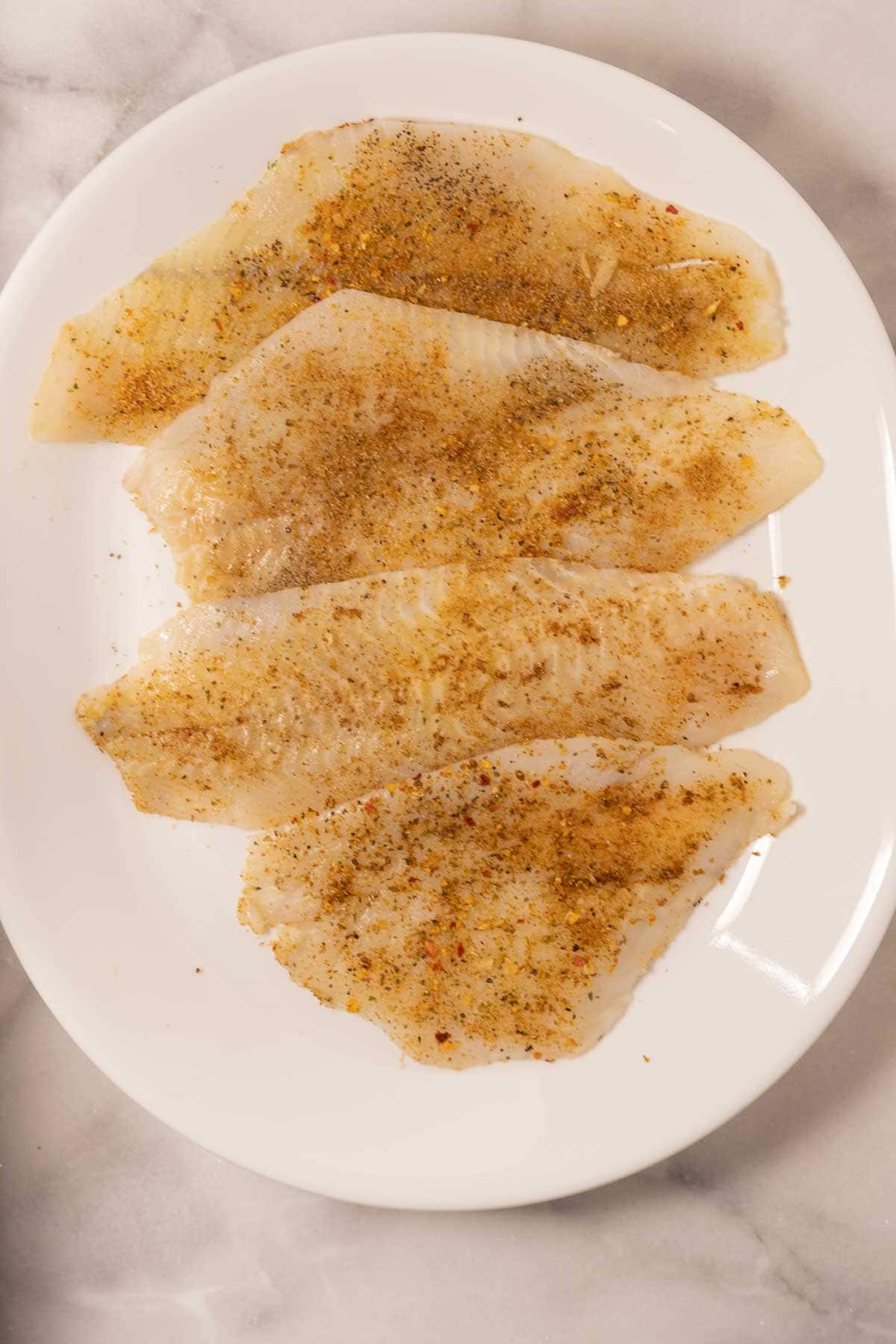 Seasoned flounder on white plate.