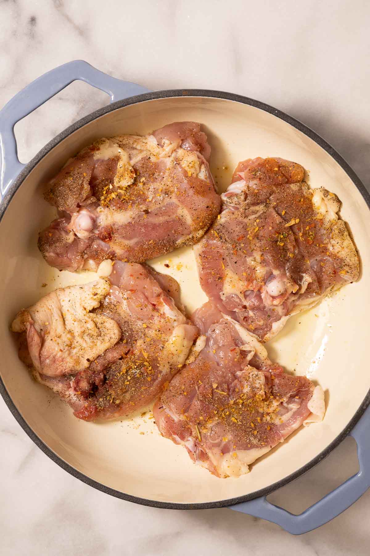 seasoned chicken thighs in skillet.