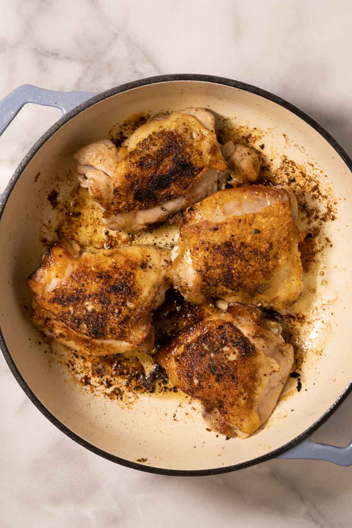 Browned chicken thighs in skillet.