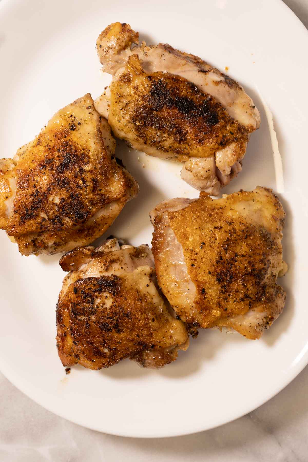 Browned seasoned chicken thighs on platter.