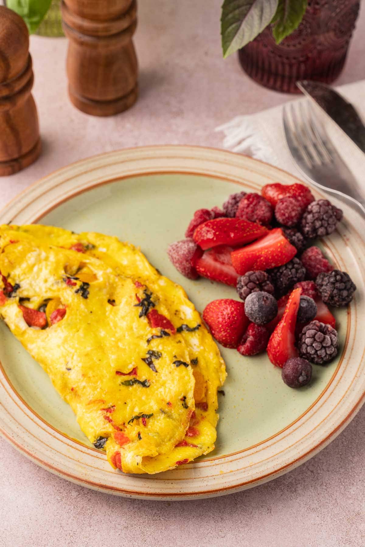 Basil tomato omlette with berries on plate.