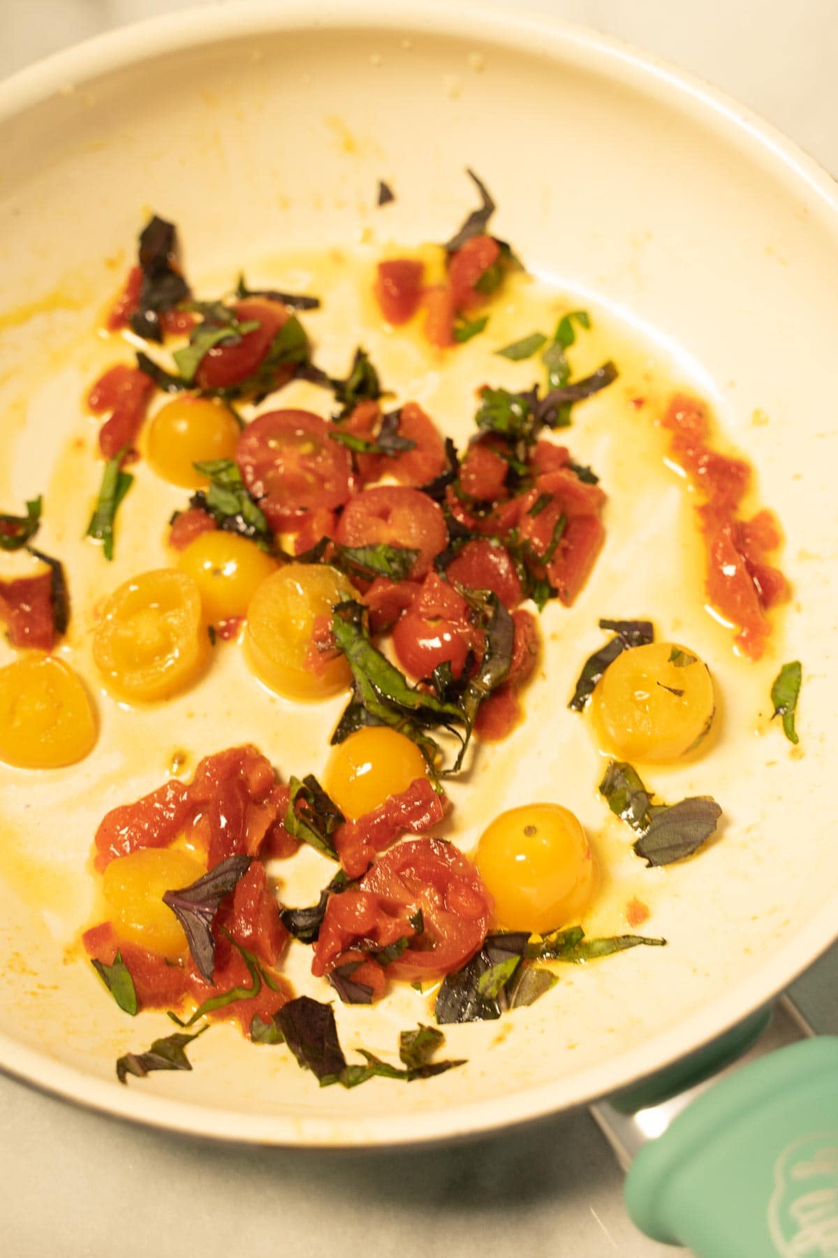 Sautéed tomato and basil in skillet.