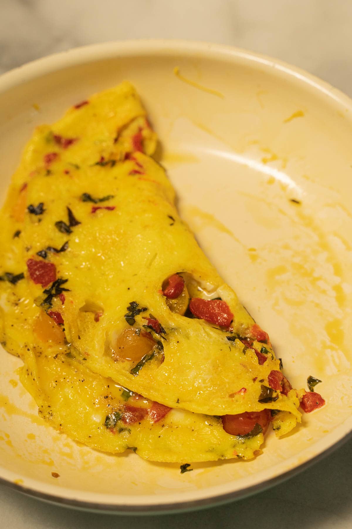 Basil, tomato and red pepper omleette in skillet.