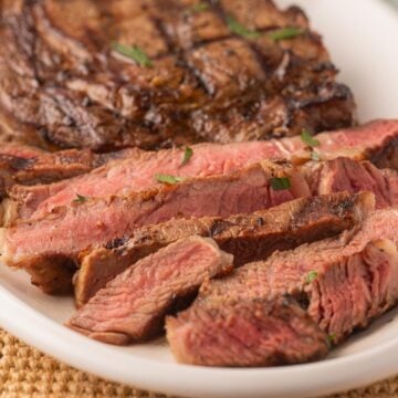 Sliced Beer Marinated Steak on white platter.