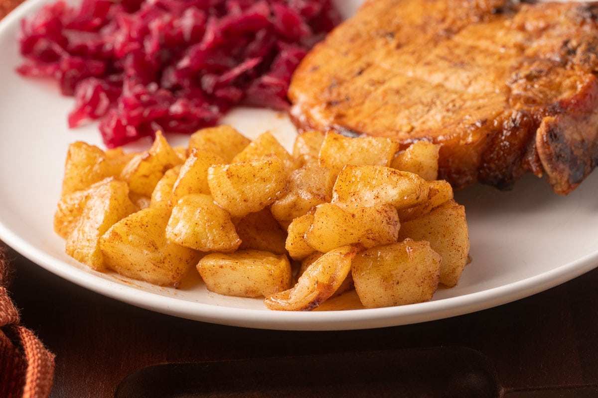 Air Fryer Apples, pork chop and red cabbage on white plate.