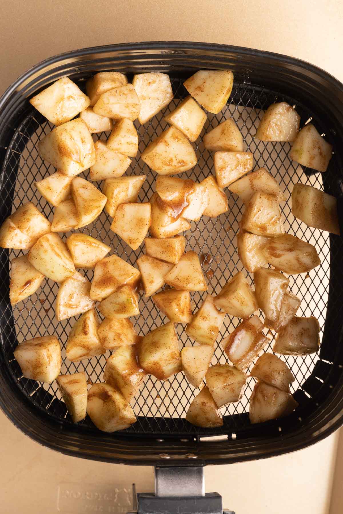 Chopped, seasoned apples in air fryer.