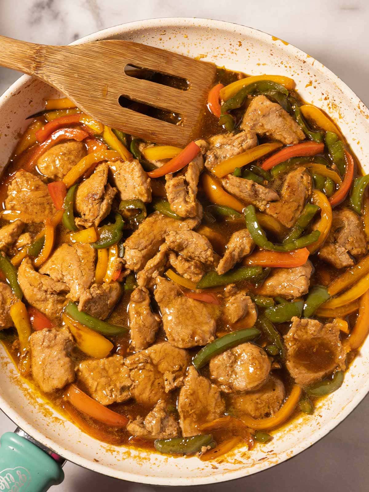 Pork and peppers stir fry in skillet.