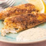 Pan fried flounder fillets with garlic basil sauce on green plate.